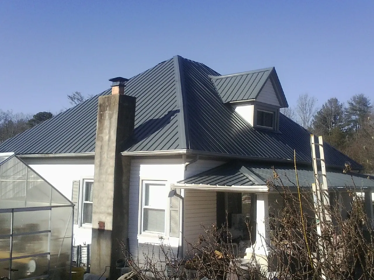 Dark blue standing seam metal roof on a white farmhouse with dormer — Slate & Tile Roof Repair by Roofing Brothers in Los Altos