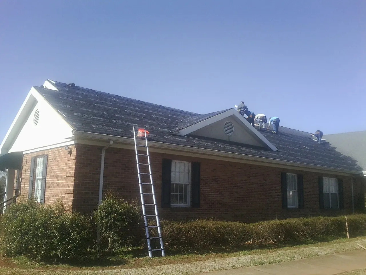 Crew tearing shingles off a brick ranch roof with a ladder set — Metal Roof Repair work by our crew in Los Altos