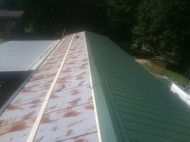 Old rusted panels beside newly installed green metal roofing — Wind Damage Roof Repair by Roofing Brothers in Los Altos