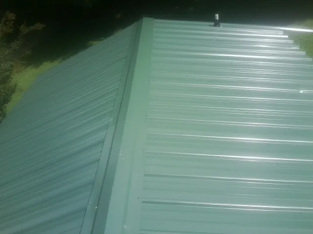 New green metal panels meeting at the ridge of a roof — Flat Roof Repair work by our crew in Los Altos