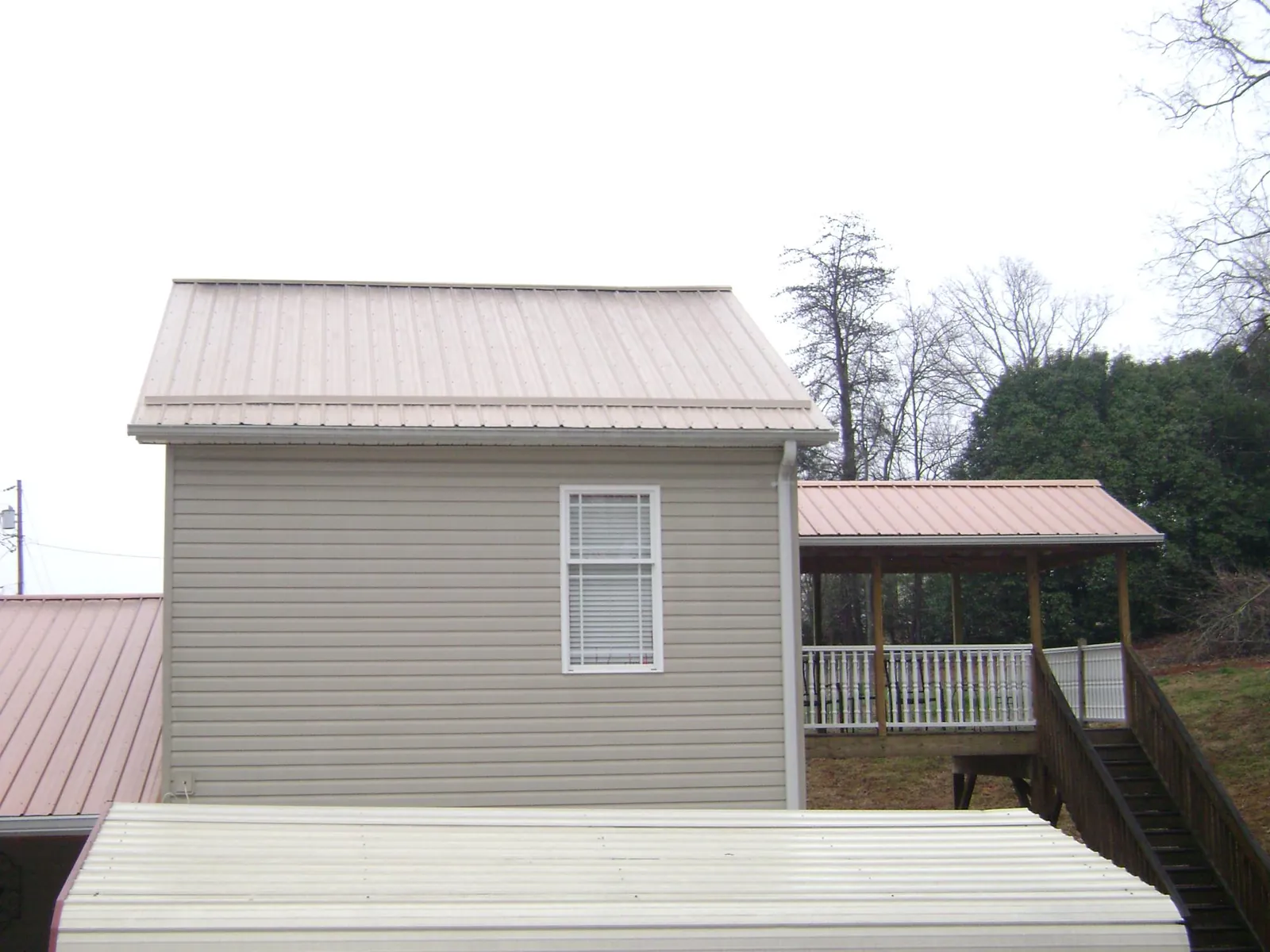 Tan metal roofs on a two story addition and attached porch, from a Roof Replacement job in Los Altos
