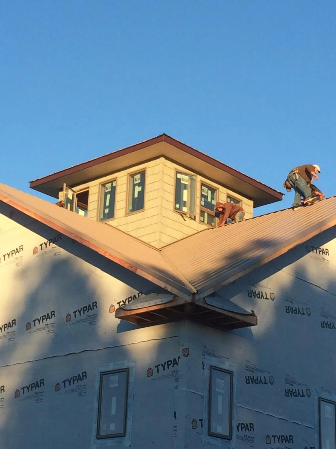 Roofers working around a rooftop cupola on a new metal roof at sunset — Roof Waterproofing in Los Altos by Roofing Brothers